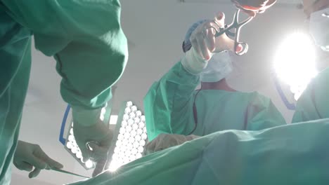 diversos cirujanos con batas quirúrgicas operando a un paciente en el quirófano, cámara lenta