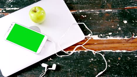 mobile phone and green apple on laptop