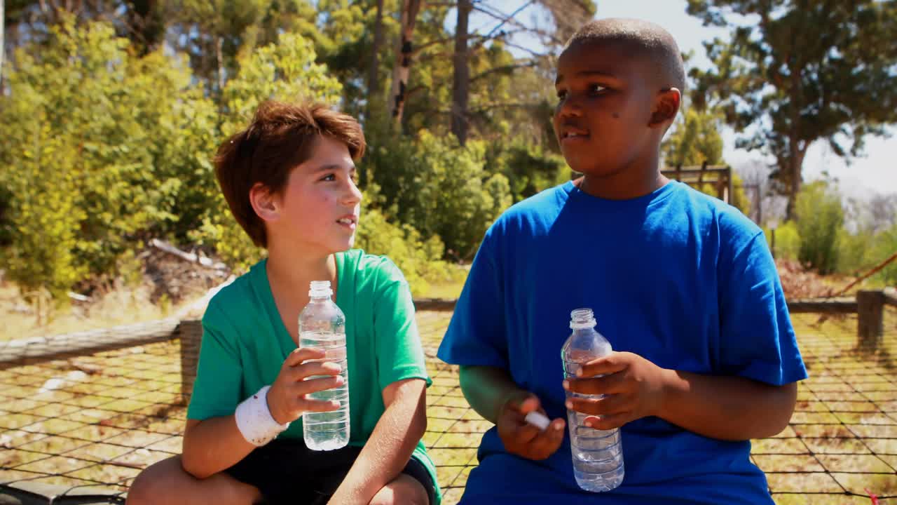 niños bebiendo agua después del entrenamiento durante una carrera de obstáculos