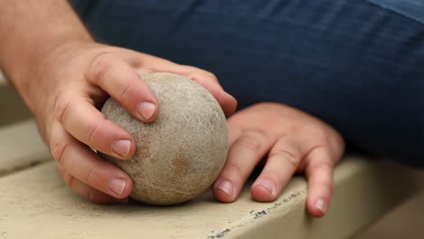 close-up of hands holding a stone ball