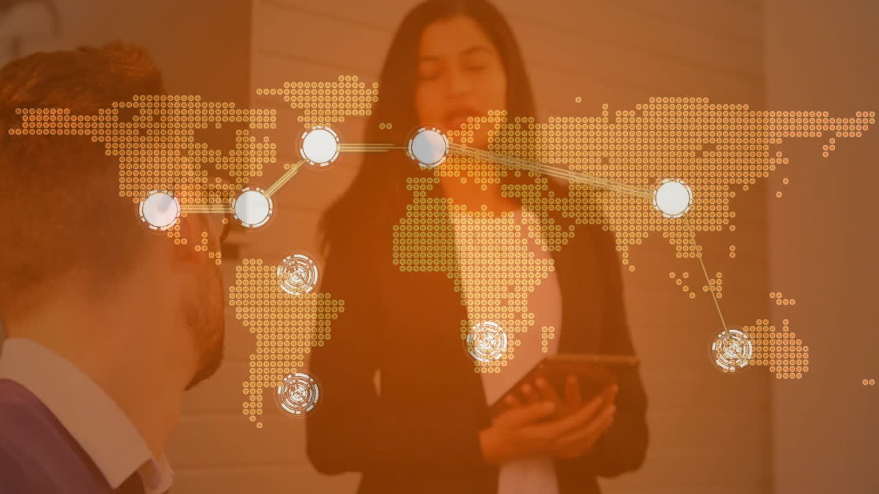Male coworker listening to female speaker in tech office, with world map overlay tracing nodes