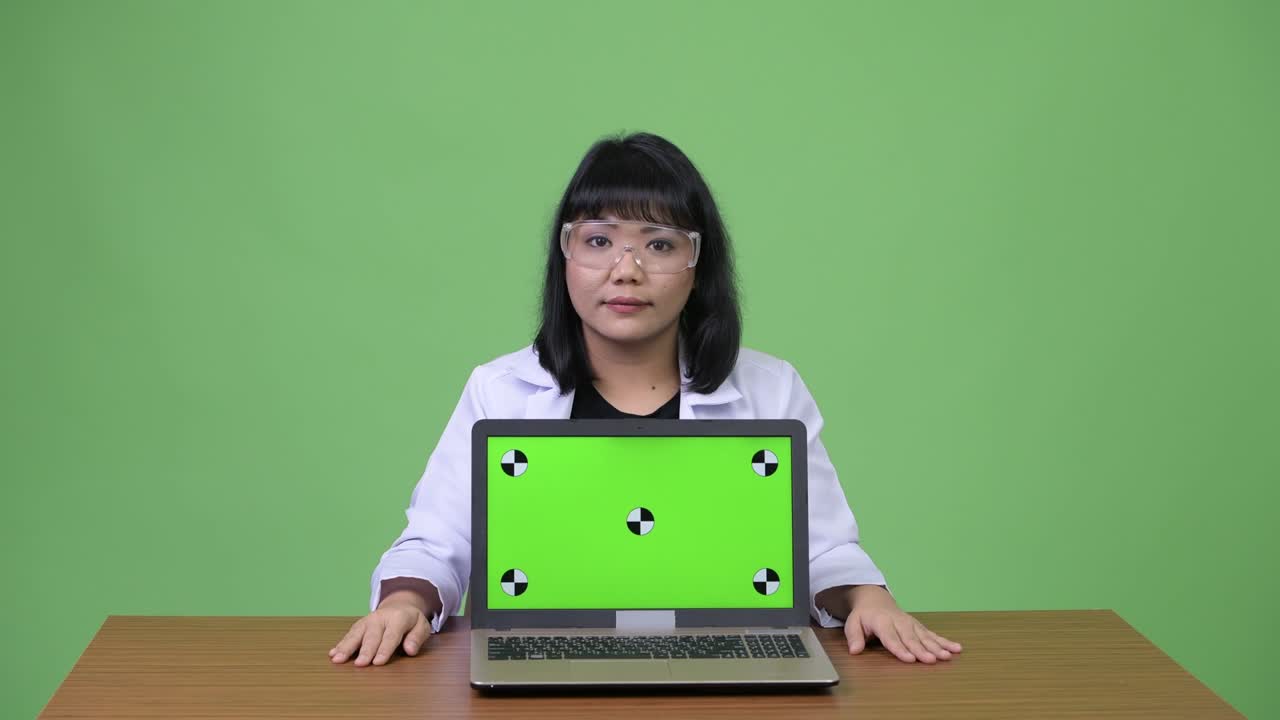 Beautiful Asian woman doctor wearing protective glasses showing laptop