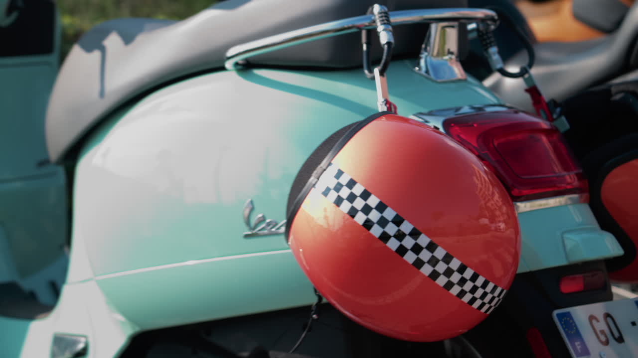 Cannes, France - October 12, 2025: Detail shot of a mint green Vespa with an orange helmet featuring a checkered stripe