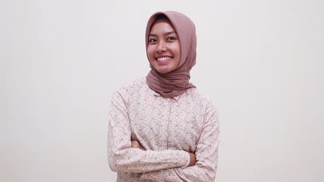 pretty young asian muslim girl standing with folded hands while looking at the camera and smiling