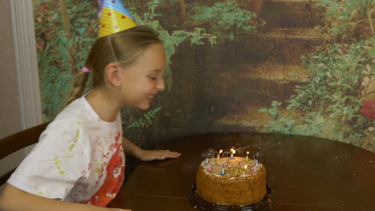 Funny girl and her father can not blow birthday candles on cake. Joke party at home. Young girl with adult man blowing candles on cake. Lot of smoke and ash on table. Girl clapping. Fast motion effect