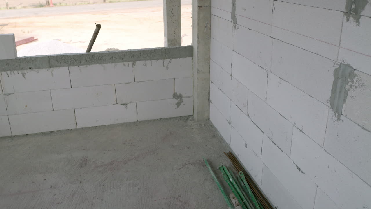 Panoramica dell'inquadratura che mostra alcuni blocchi impilati uno sull'altro e rivela una stanza in costruzione all'interno di un edificio