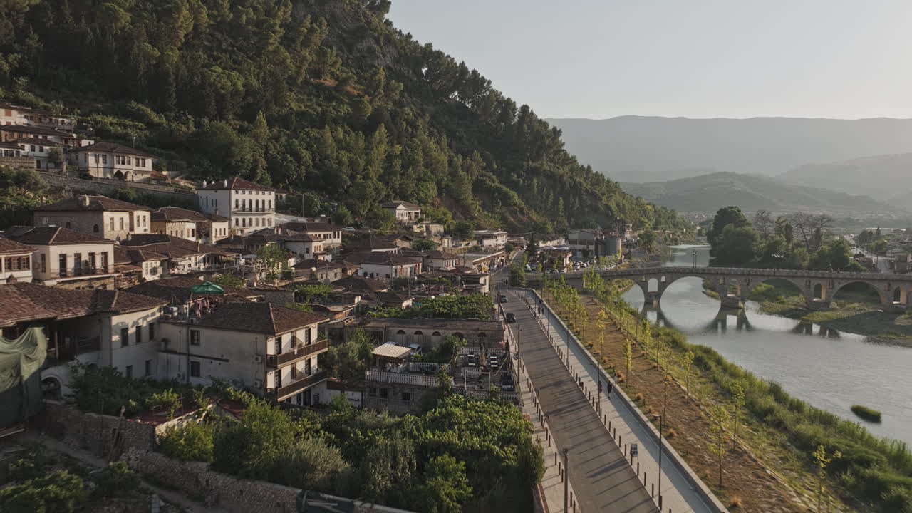 Berat, Albania. Sorvolo a bassa quota v13 di Rruga Kristaq Tutulani lungo il fiume Osum, che cattura il paesaggio urbano del quartiere di Gorica e la montagna collinare al tramonto - Ripreso con Mavic 3 Pro Cine - 11 luglio 2024