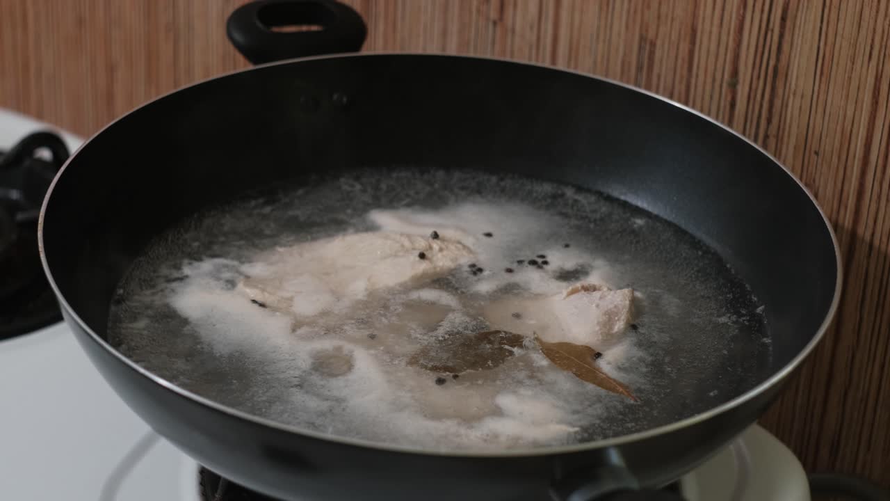 Homemade chicken broth boiling and cooking in a pot - static close-up shot