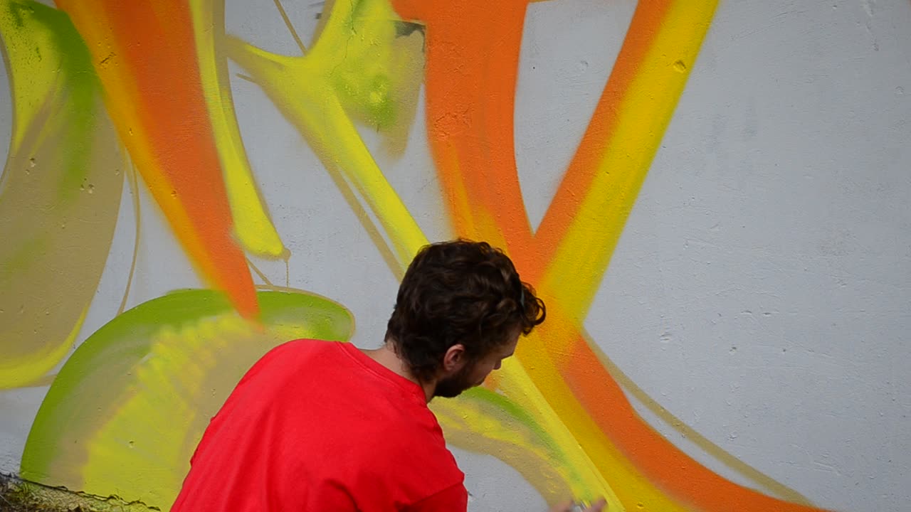 The artist draws graffiti on a fence, abstraction