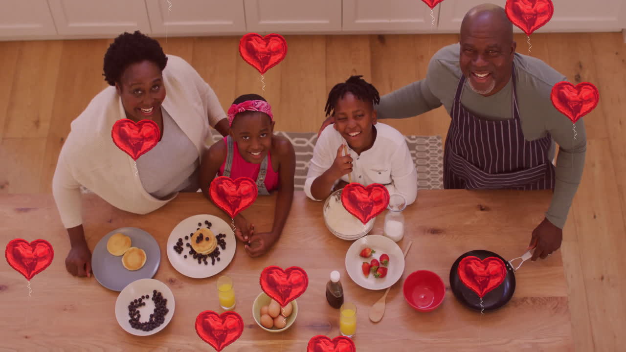 улыбающаяся семья наслаждается завтраком вместе с красными сердечными анимациями, плавающими над ними.