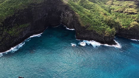 Vista-Aérea-De-La-Costa-Azul-Y-Las-Olas-Rompiendo-A-Lo-Largo-De-Las-Colinas-Ondulantes-En-Kauai-Hawaii