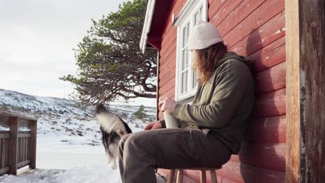 the man is relishing a warm drink with his dog nearby in the winter season in bessaker, trondelag county, norway - static shot