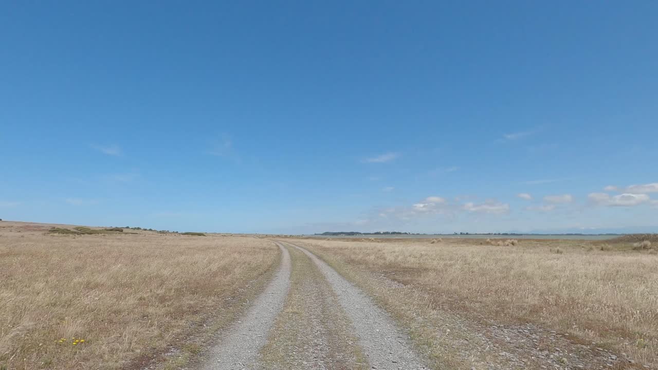 POV off-road cycling on 4WD track as land narrows to meet lake and sand dunes - Kaitorete Spit and Lake Ellesmere (New Zealand)