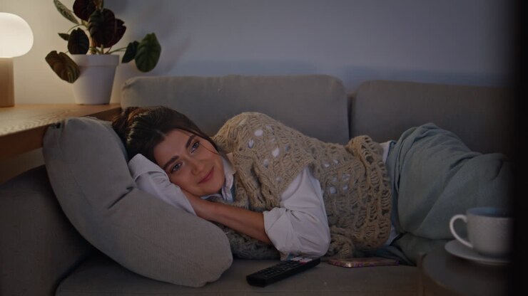 lächelnde brünette wechselt tv-kanäle entspannende couch spät in der nacht allein closeup