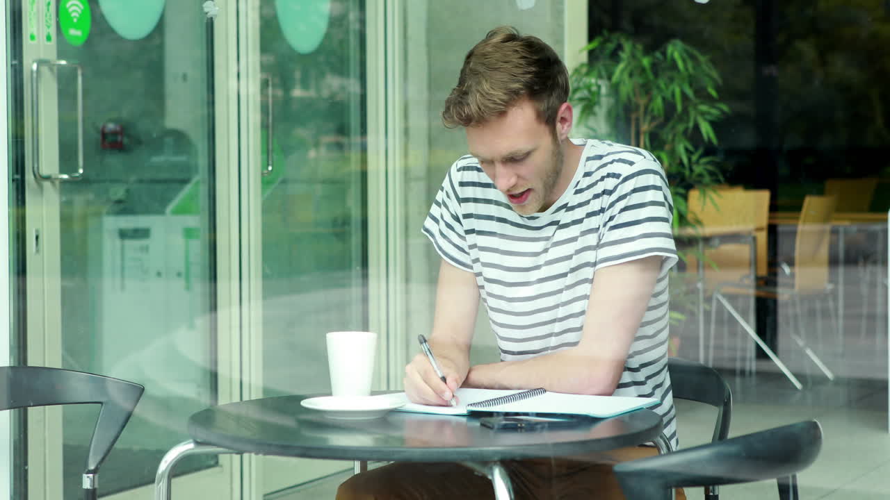Smilende student med kaffe skriver