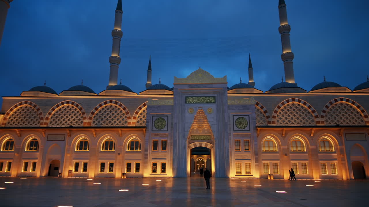 View of the Camlica Mosque in Istanbul at evening, Turkey. Facade made of white stone, illumination, few people in front of it