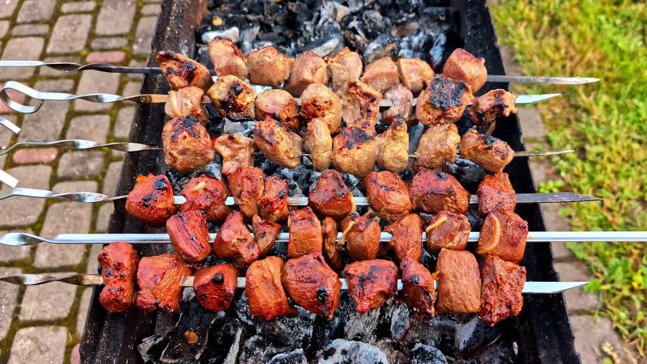 Meat skewers over grill with charred surface and grill marks from fire