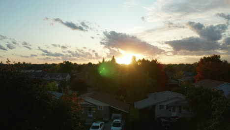 Drone-aerial-view-ascending-over-the-suburbs-to-reveal-a-sunset-at-dusk-during-autumn