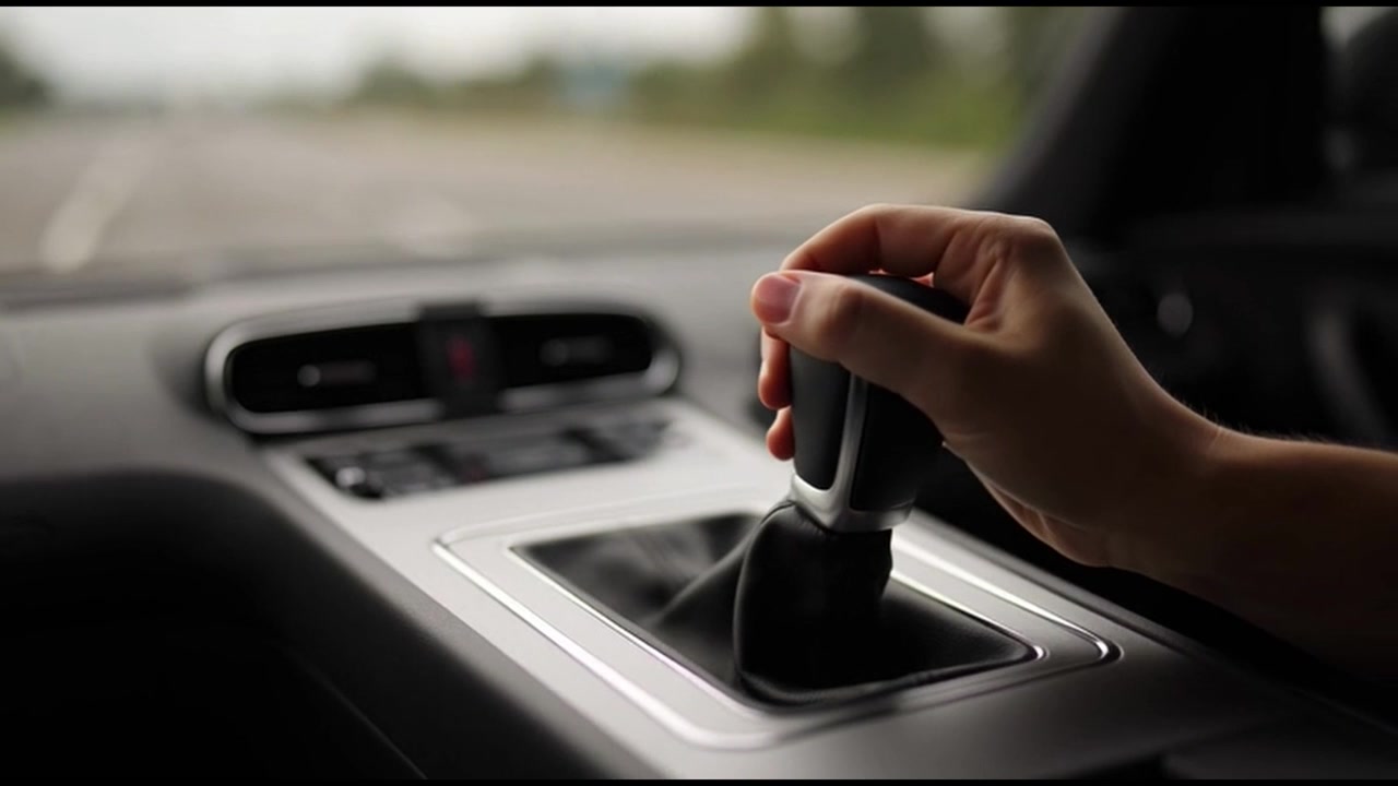 Mano del conducente appoggiata sulla leva del cambio in un'auto in movimento