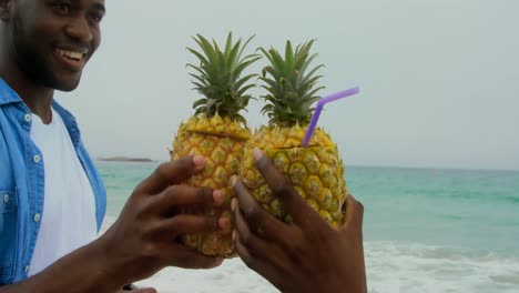 african american couple toasting pineapple juices on the beach 4k