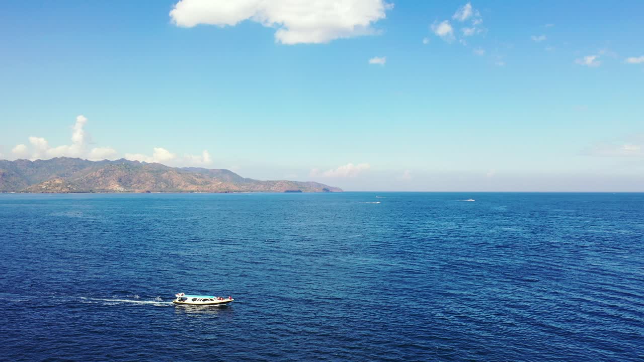 깊고 푸른 바다를 건너는 관광객들과 함께 여행하는 보트, 발리의 흰 구름이 있는 밝은 하늘 배경의 열대 섬 만에 접근