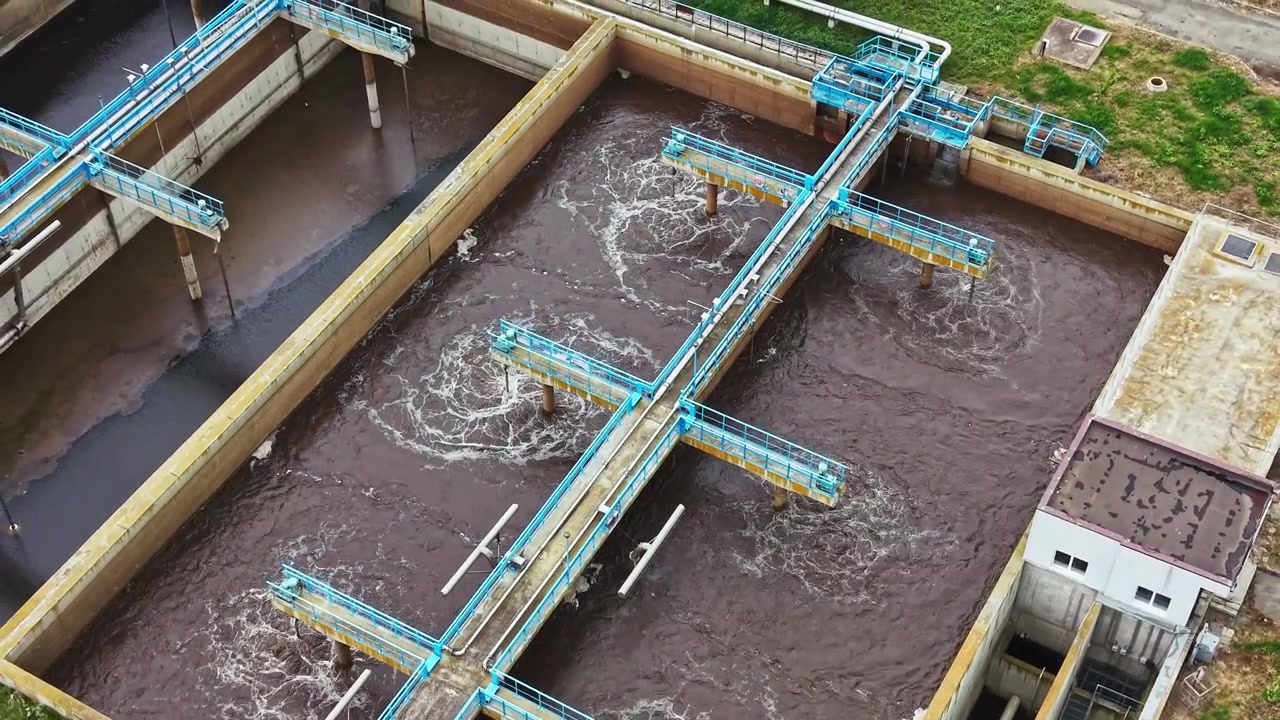 Immagini del trattamento delle acque. Bacino di aerazione con fanghi attivi e schiuma. Impianto industriale di trattamento delle acque reflue che mostra bacini di aerazione e infrastrutture di controllo dall'alto.