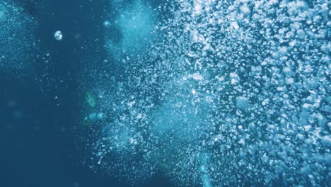 scuba divers working on an underwater ocean structure let out a stream of bubbles from deep below