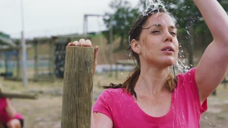 mujer caucásica vertiendo agua en su cara en el campamento de entrenamiento