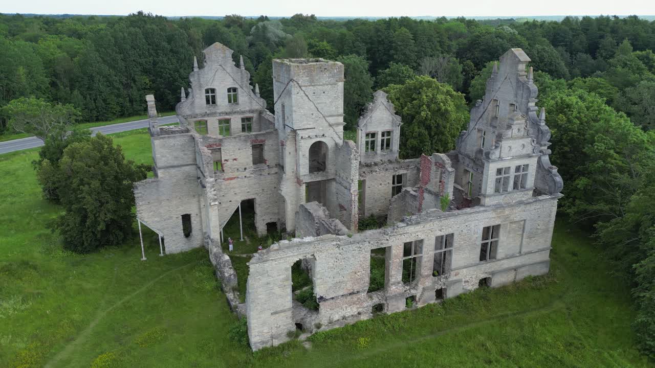 Two people explore long abandoned ruins of Ungru Castle in Estonia
