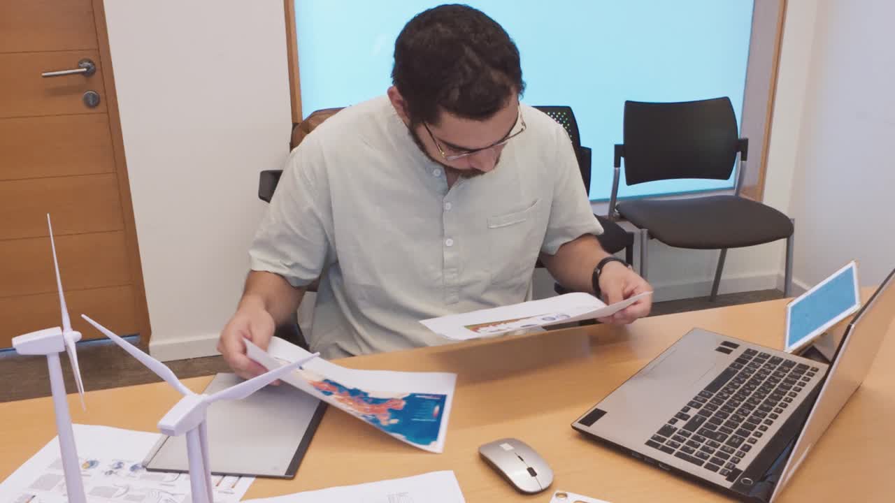 Man Working at Desk with Wind Turbine Model