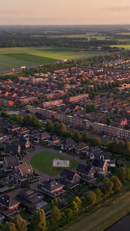 aerial view of a suburban residential area with houses and green fields at sunset