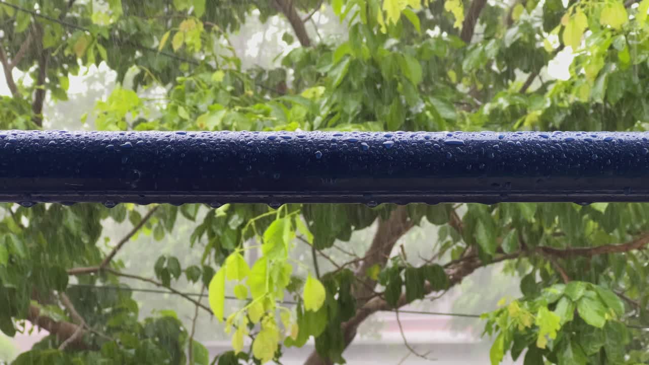 Closeup of Metal Pipe with water droplets on the surface during the heavy rain, droplets on the metal pipe with heavy rain with the wind on the background