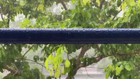 closeup of metal pipe with water droplets on the surface during the heavy rain, droplets on the metal pipe with heavy rain with the wind on the background