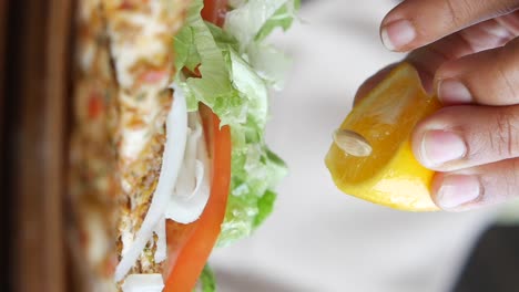 person squeezing lemon juice over a turkish pide