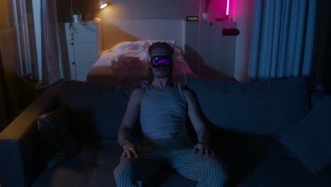 man wearing vr headset on couch at night.