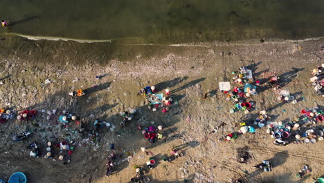 Bird's-eye-view-of-people-working-on-beach-in-Mui-Ne-bay,-Vietnam-early-morning-cleaning-and-sorting-fish-seafood