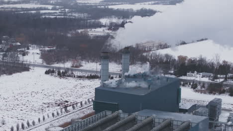 planta industrial cubierta de nieve con chimeneas, entorno de invierno, vista aérea