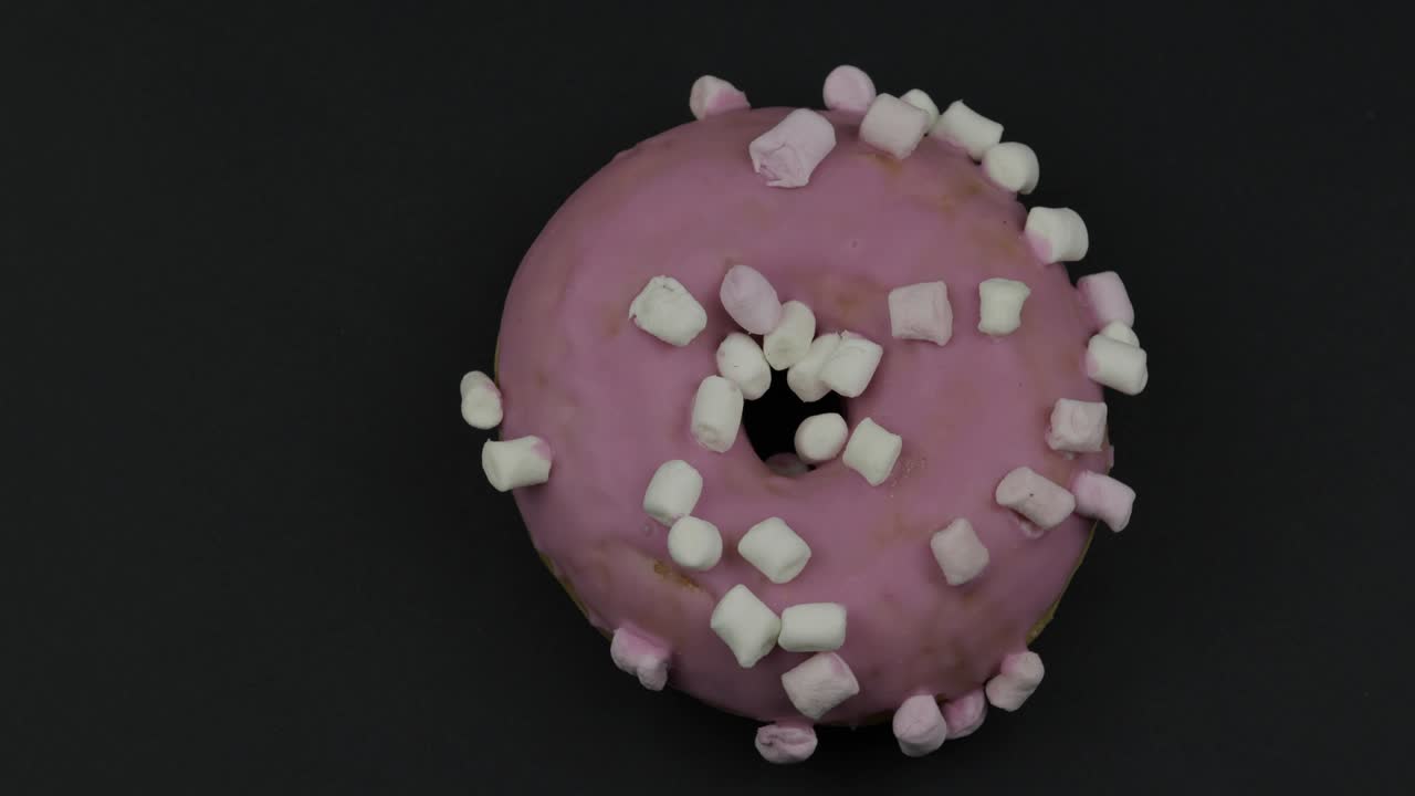 donut dulce girando sobre un fondo negro. vista superior. donut sabroso y fresco