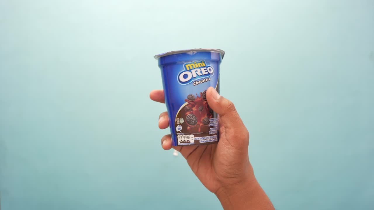 mano sosteniendo una taza de galletas de chocolate mini oreo