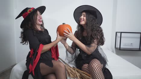 two witches holding a pumpkin