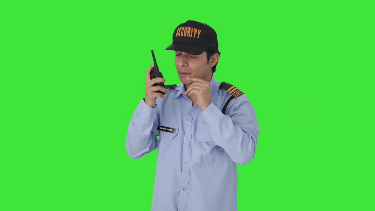 Guardia di sicurezza indiana arrabbiata che dà istruzioni con un walkie-talkie su schermo verde