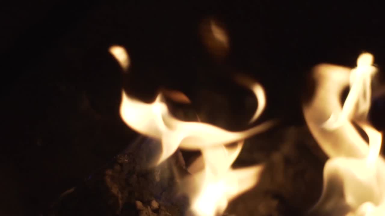 Close up of glowing red logs burning in a fire pit on a cool summers night