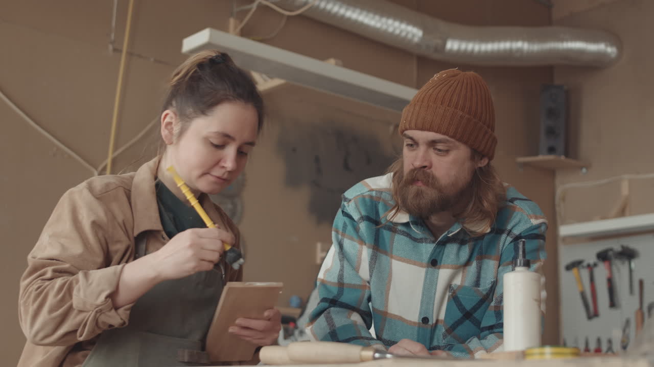 Professional Joiner Teaching Young Woman in Workshop