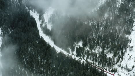 Luftaufnahme-Eines-Vorbeifahrenden-Zuges-In-Einem-Nebligen-Winterwald