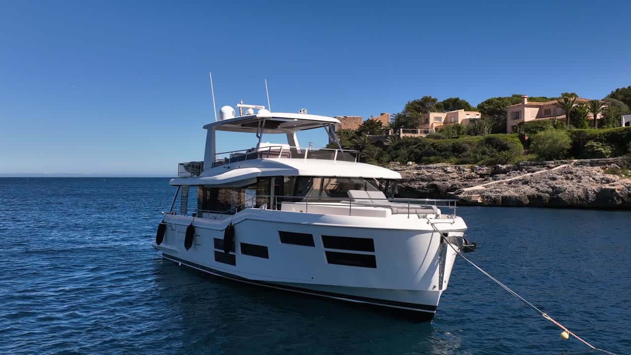 Ripresa con drone di uno yacht di lusso accanto a ville su una scogliera in estate al rallentatore