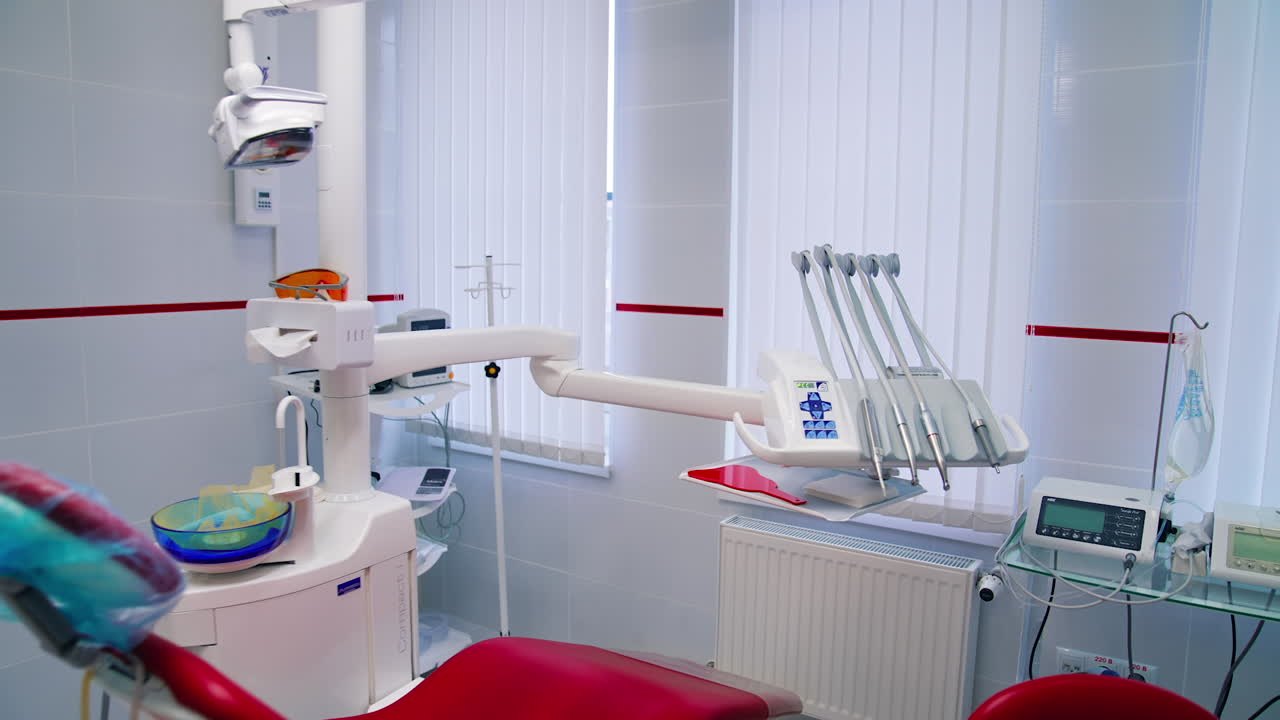 Modern dental cabinet. Empty stomatology office with clean medical tools near the red dental chair. Dentistry concept.
