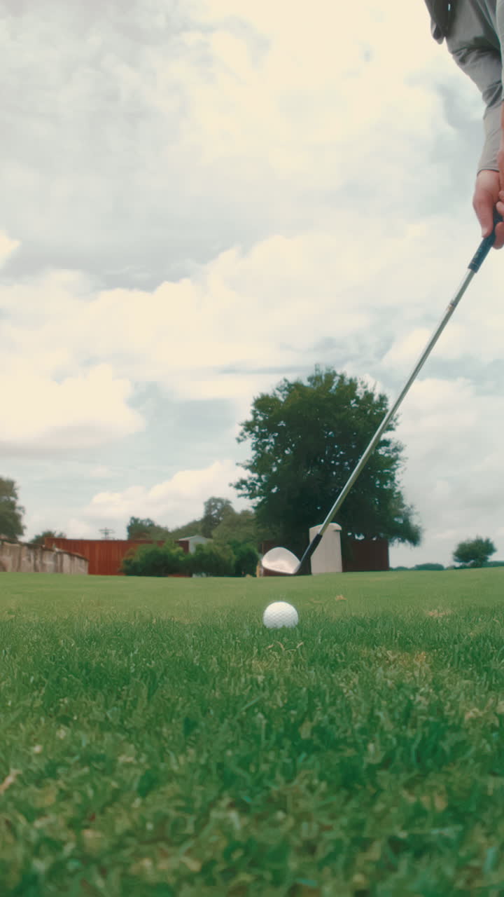 Extreme slow-motion vertical view of golfer executing a precise chip shot directly at camera. Highlights technique, ball flight, and short game action