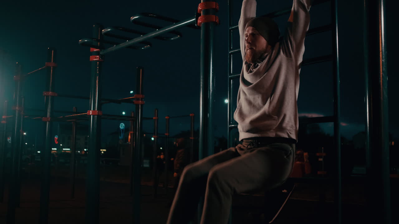 hombre haciendo pull-ups por la noche en un parque