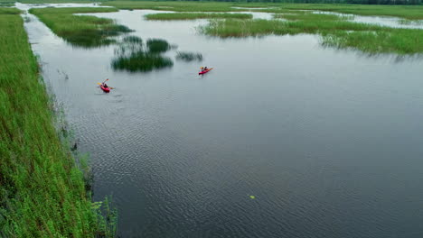 aerial drone zoom out rowboat sailors in estuary river water landscape paddling