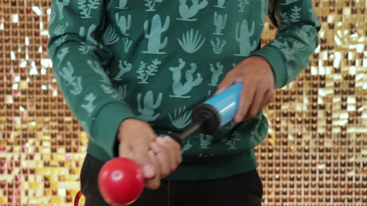 hombre inflando un gran globo rojo con bomba de mano, telón de fondo dorado